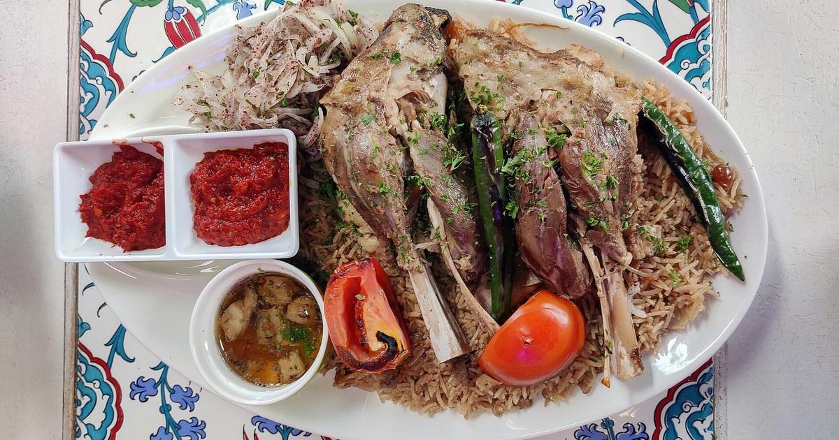 Büyük bir tepside baharatlı pirinç pilavı üzerinde ateşte pişmiş et: Yemen usulü mendi