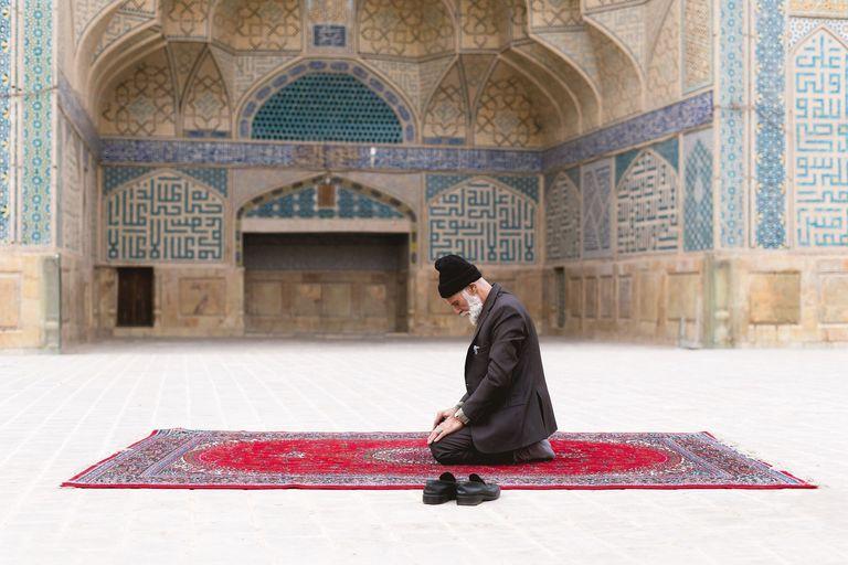 İsfahan Cuma Camii'nin avlusunda seccadesinde dua eden yaşlı bir adam